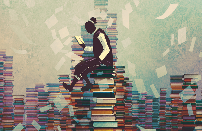Man sitting on piles of books reading